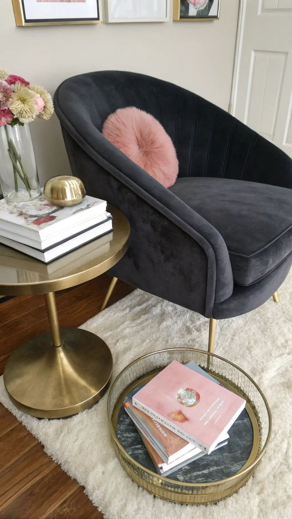 Overhead view of a seating area with a charcoal velvet chair, a round brass side table, and a cream area rug, featuring stacked art books with a pink agate coaster. Romantic Moody Bedroom Ideas Pink