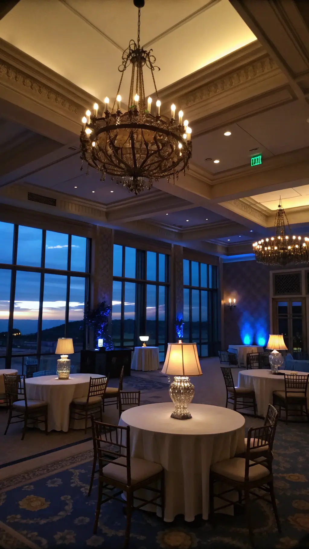 Wide-angle view of a room during blue hour; chandelier dimmed at 50%, table lamps casting warm light, and LED accent lights adding a subtle glow, creating a moody ambiance. Romantic Moody Bedroom Ideas Pink