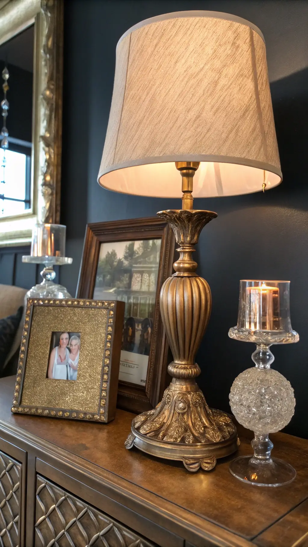 Close-up of metallic vignette featuring aged gold lamp, copper picture frame, and crystal candlesticks against dark walls. Romantic Moody Bedroom Ideas Pink
